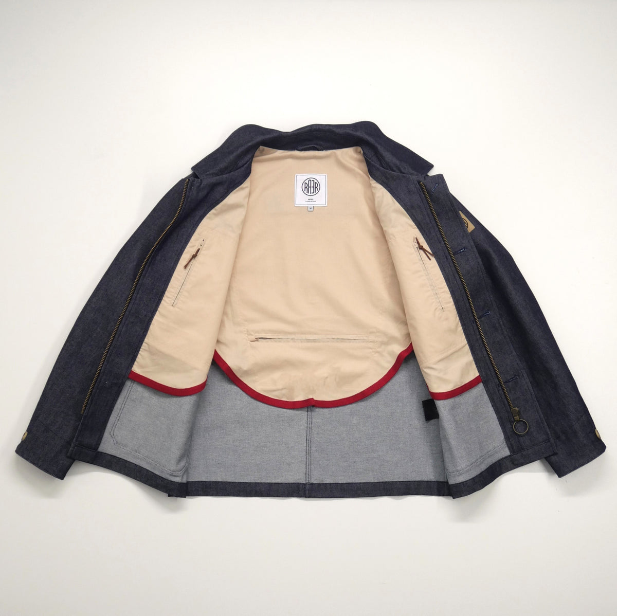 Veste ARTIST Denim ouverte à plat, avec la demi-doublure claire bordée de rouge.