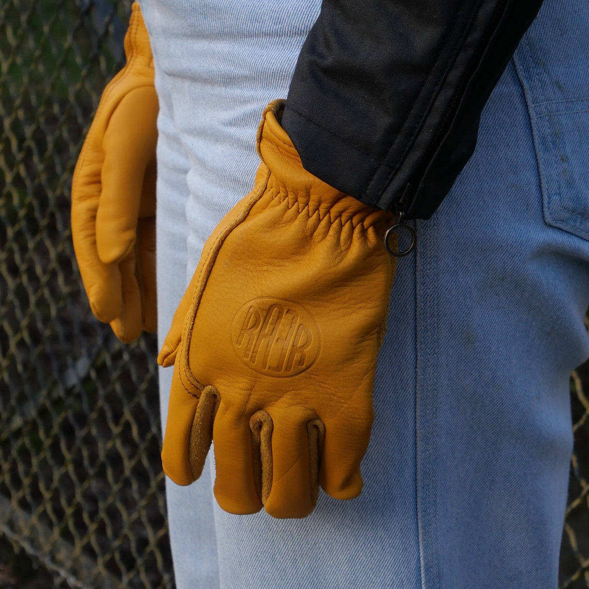 Gants APPLE 2 Gold portés avec une veste noire et un jean clair.