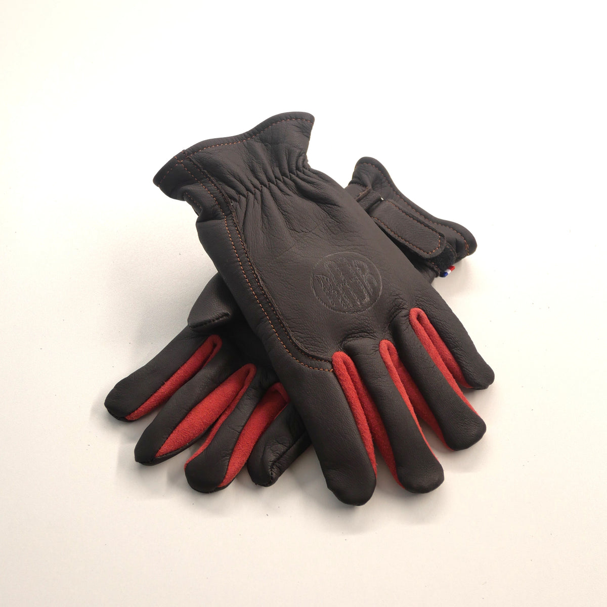Paire de gants APPLE 2 marron posée sur fond clair, avec empiècements rouges entre les doigts.