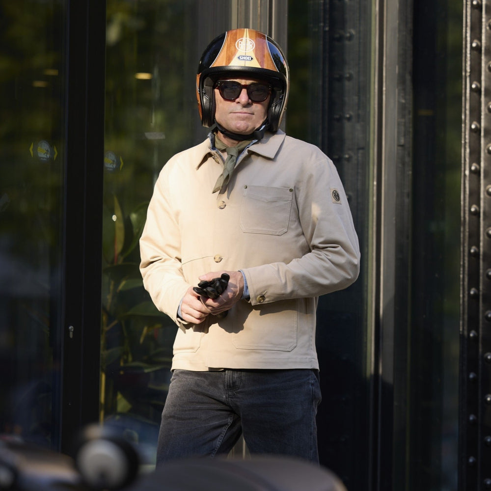 Veste ARTIST beige portée debout avec un casque, des gants à la main.