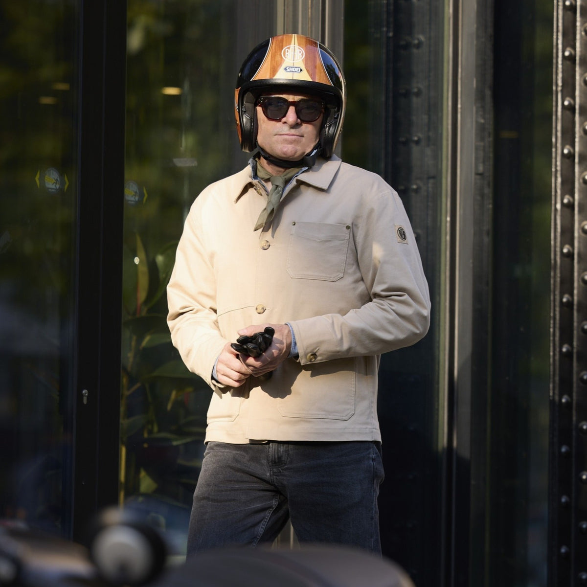 Veste ARTIST beige portée debout avec un casque, des gants à la main.