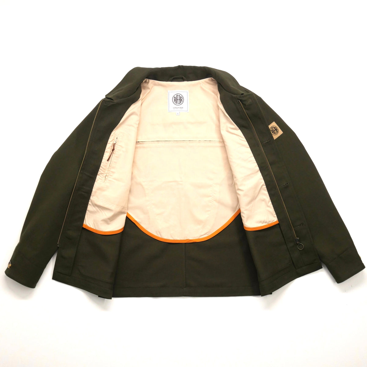 Veste ARTIST kaki ouverte à plat, montrant la demi-doublure claire bordée d’orange.
