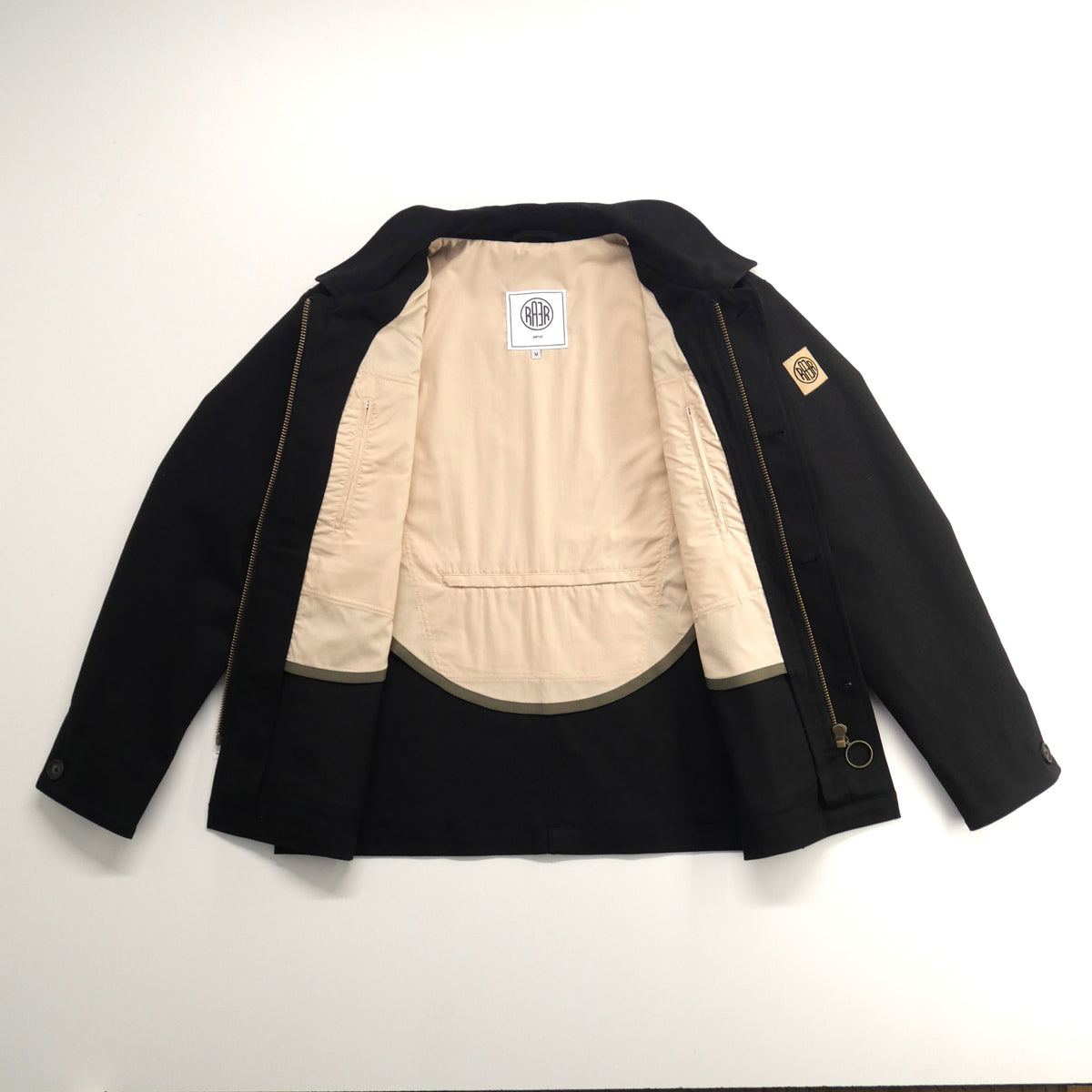 Veste ARTIST noire ouverte à plat, montrant sa demi-doublure claire.
