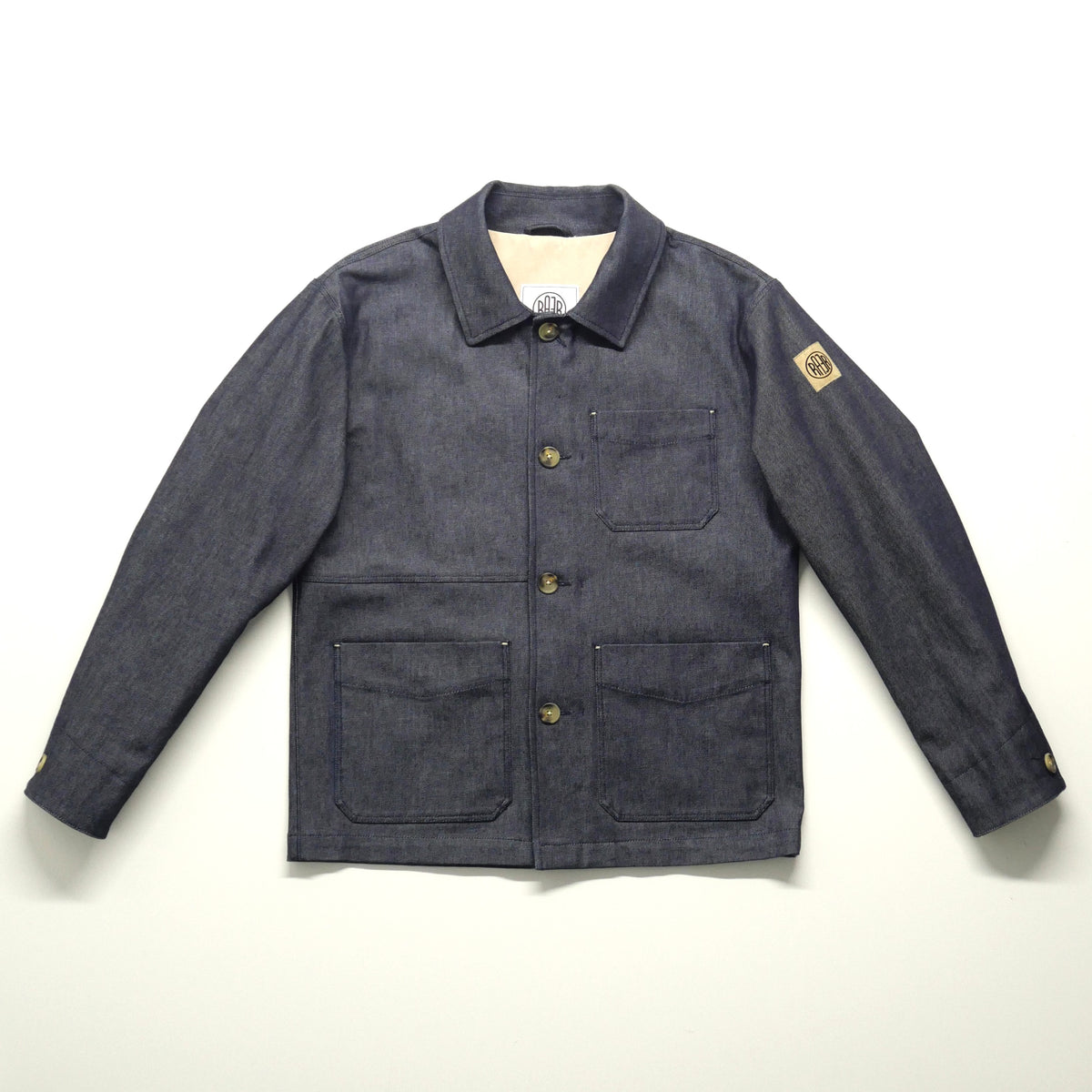 Veste ARTIST Denim posée à plat, vue de face avec ses poches plaquées et son boutonnage.