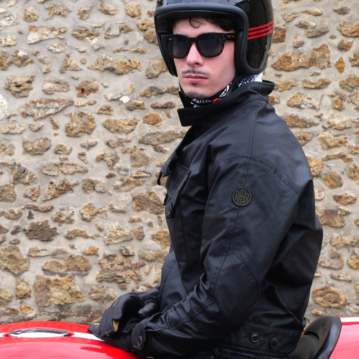 Veste ASCONA 2 WX noire portée de profil par un homme casqué assis sur une moto.