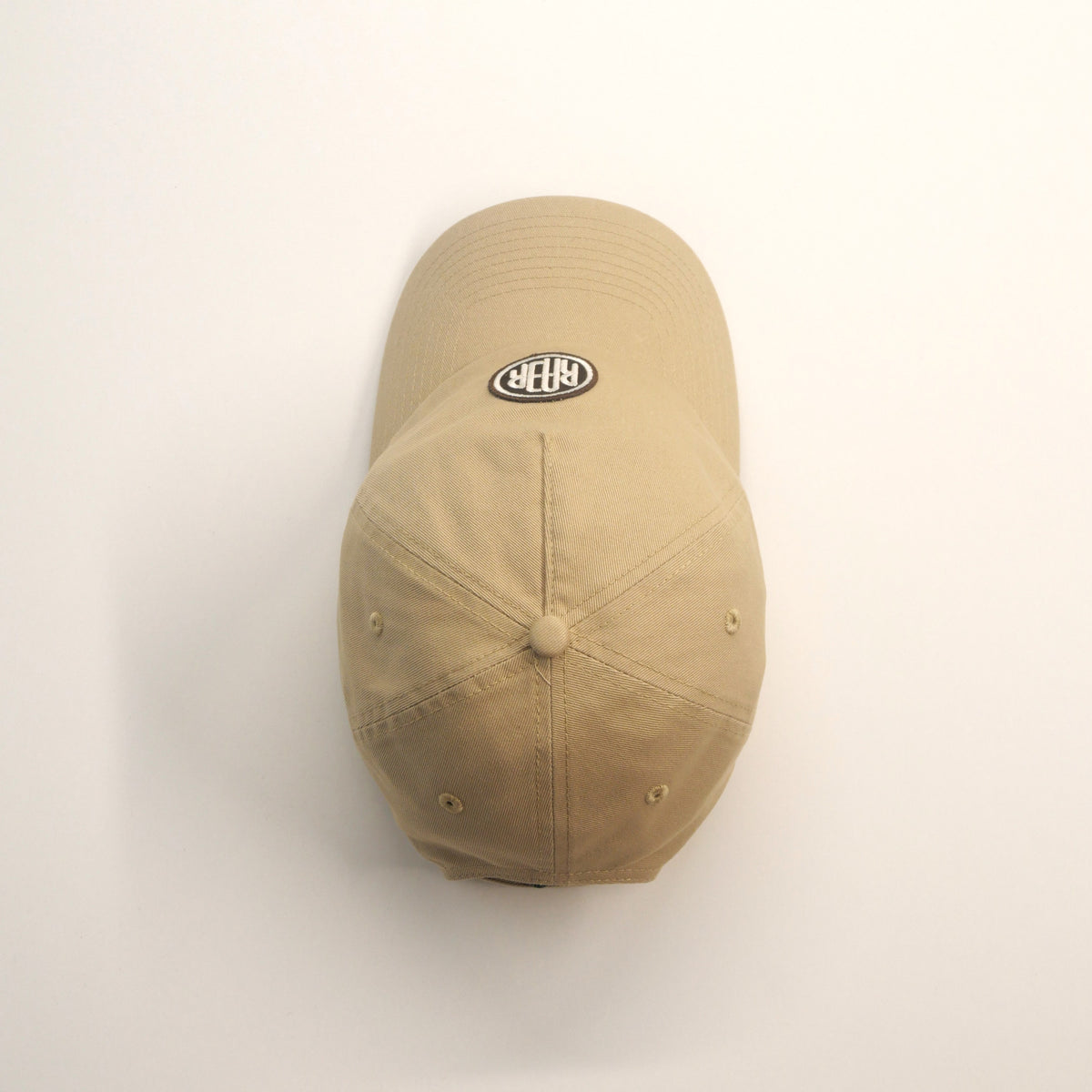 Casquette ORIGINAL beige vue du dessus, montrant le bouton, les coutures et la visière.