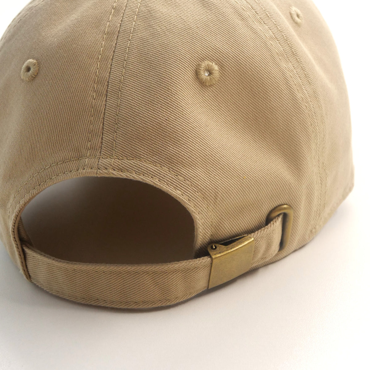 Gros plan de la bride réglable et de la boucle couleur laiton de la casquette ORIGINAL beige.