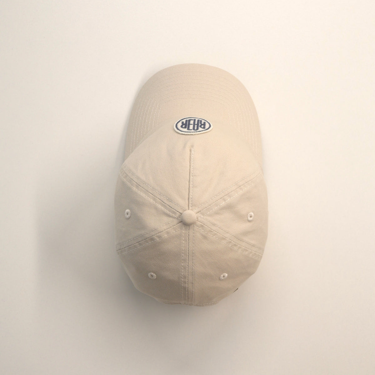 Casquette ORIGINAL écrue vue du dessus, montrant les coutures, le bouton et la visière.