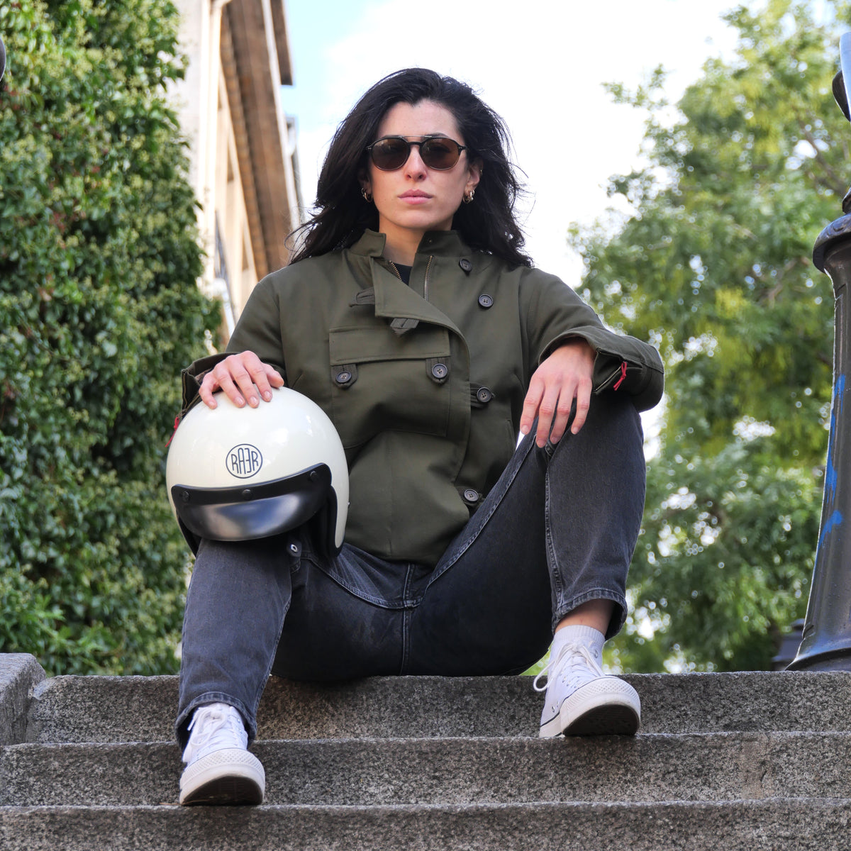 Veste DONNA Armalith kaki portée assise dans un escalier, avec un casque blanc.