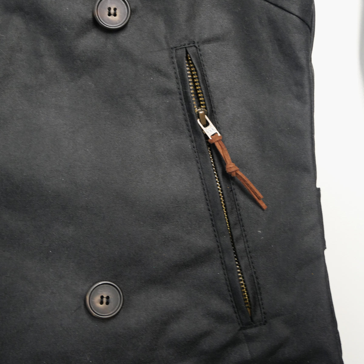 Poche zippée de la veste DONNA Wax noire, avec tirette en cuir.