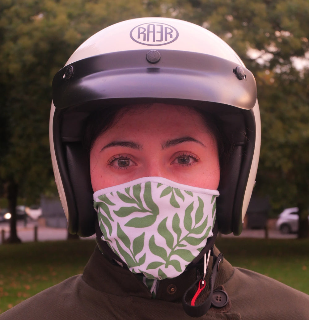 Tour de cou LEAVES à feuilles vertes porté sur le nez avec un casque blanc.