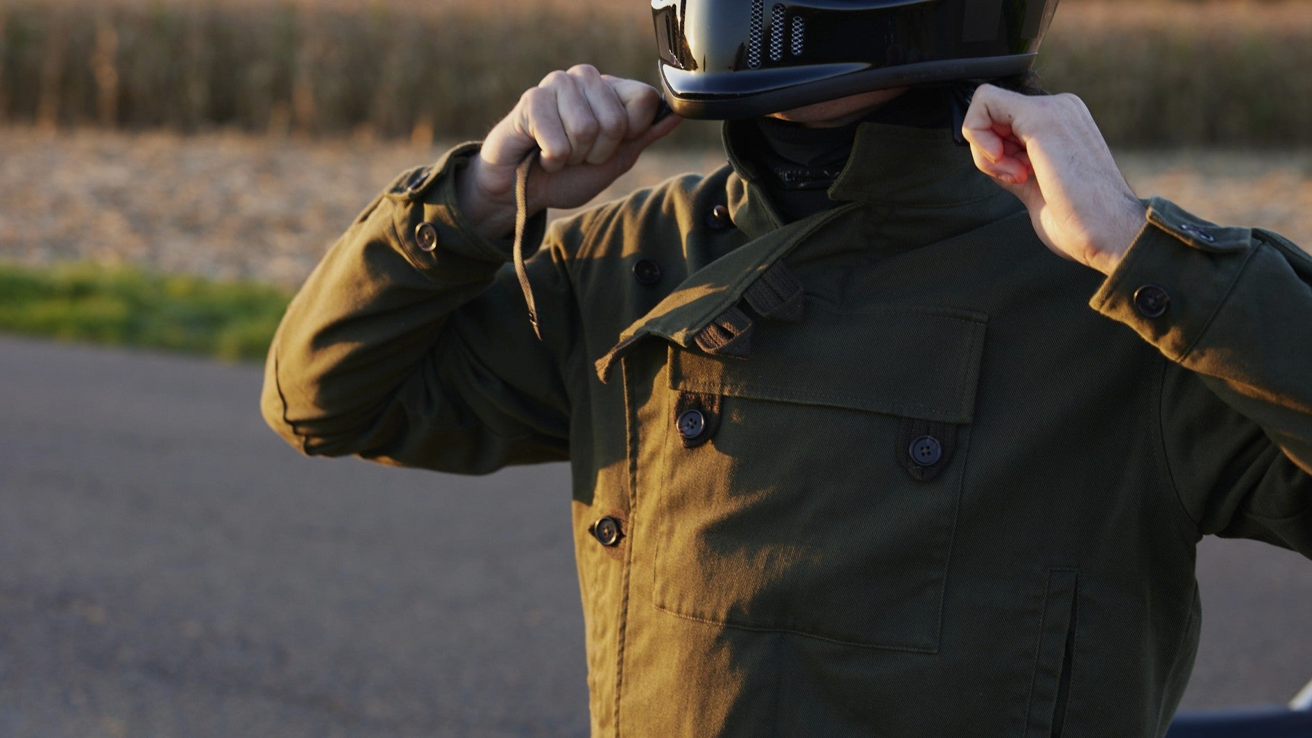 Motard ajustant son casque dans une veste RAER kaki