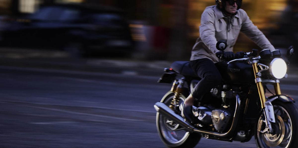 Motard portant une veste claire RAER sur une moto noire